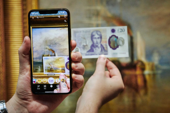 The new 20 pound note with a new Snapchat augmented reality (AR) Lens in front of the original JMW Turner masterpiece The Fighting Temeraire at The National Gallery in London