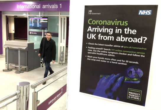A passenger walks past a coronavirus information sign at Edinburgh Airport