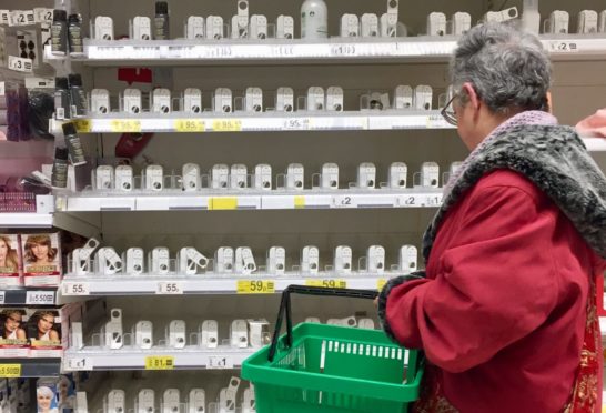 A shopper at empty soap and hand sanitiser shelves              at Asda in Toryglen, Glasgow