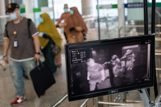 Travellers walk past a thermal scanner at the arrival terminal of Hong Kong airport