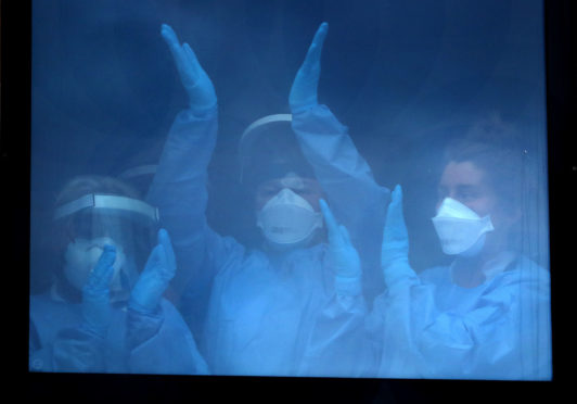 Nursing staff at the Queen Elizabeth University Hospital, Glasgow, applaud                  from behind a window during the Clap for Carers