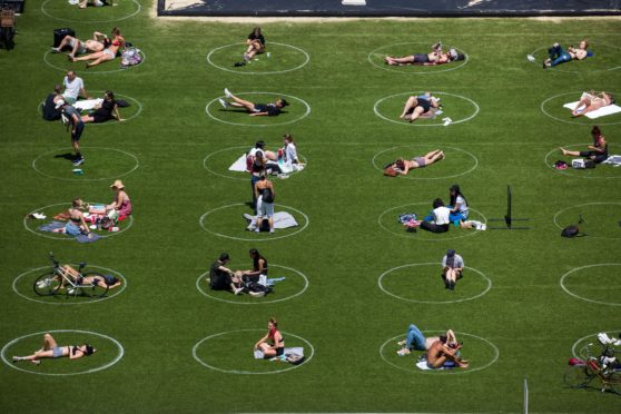 People sit inside social distancing markers at the Domino Park in Brooklyn