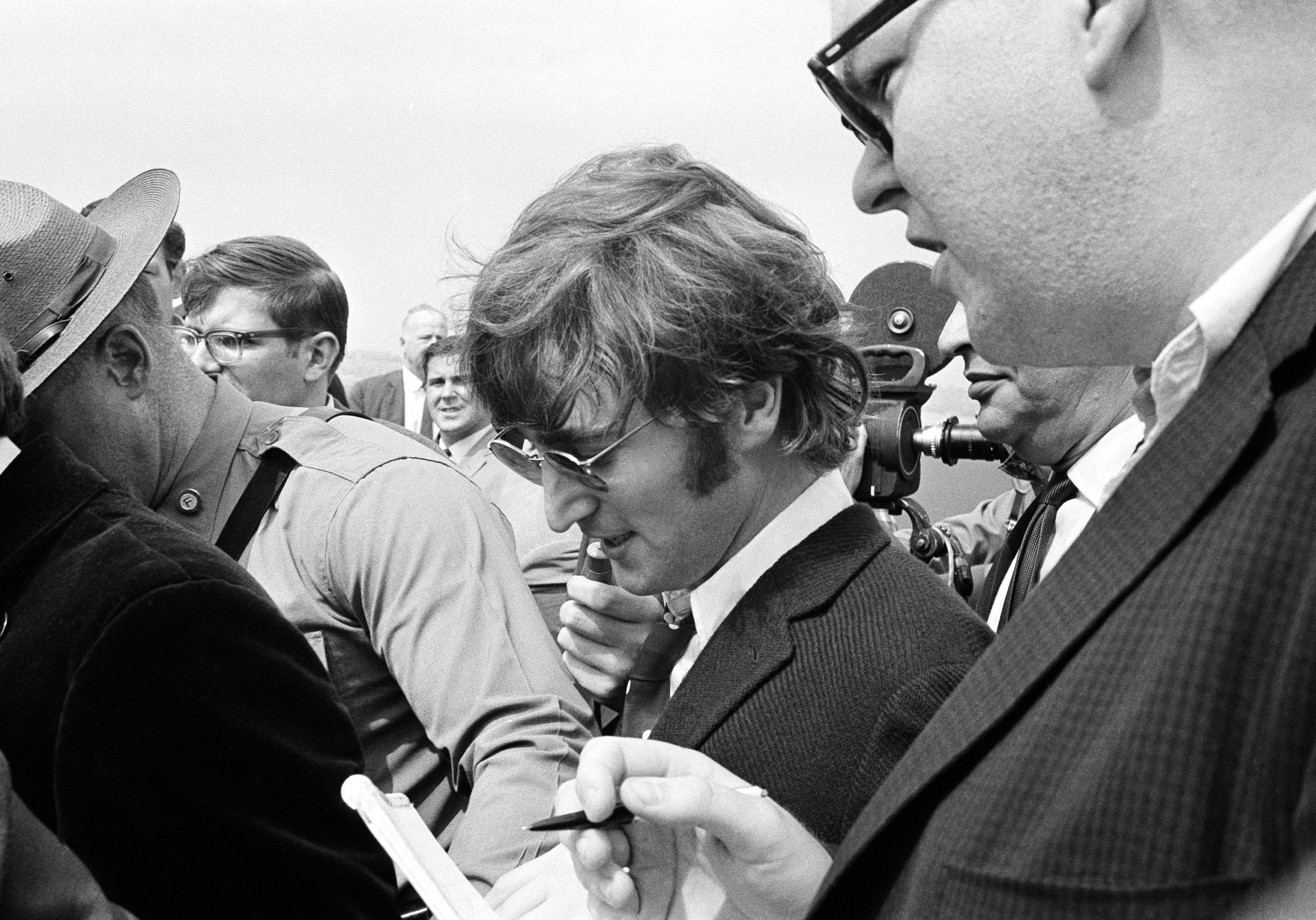 John Lennon is guided by a state trooper past journalists on arrival in Boston on August 11, 1966 for a US tour, amid a furore after he said the Beatles were more popular than Jesus