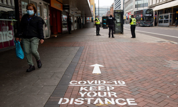 A shopper walks by social distancing instructions