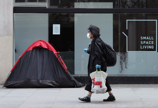 A woman walking past a homeless person's tent in London