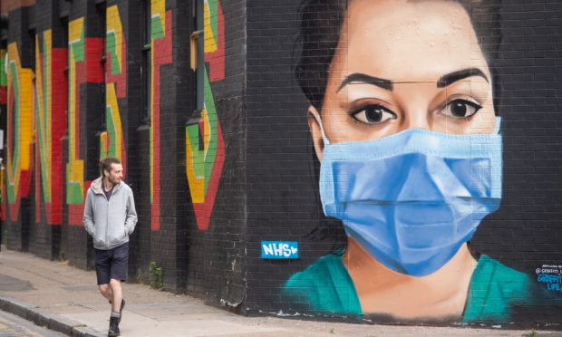 A man looks at a mural showing a nurse wearing personal protective equipment (PPE) in Shoreditch, east London