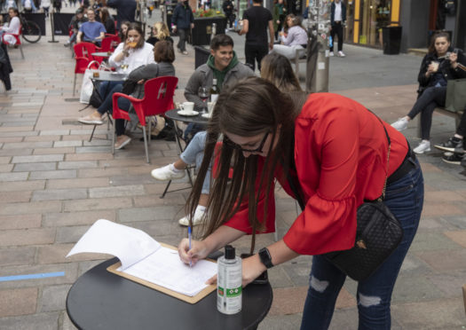 A customers fills in their contact details at the Americian NY Grill's outdoor drinking and eating area on Buchanan Street, Glasgow
