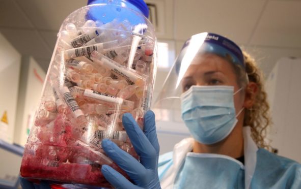 A scientist holds Covid test samples at the Lighthouse Laboratory at the Queen Elizabeth University Hospital in Glasgow