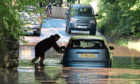 Mandatory Credit: Photo by Tina Norris/Shutterstock (10742192g)
A man abandons his car after driving it through flood water and becoming stuck on Station Road, Oakley in Fife
Flash flooding, Fife, UK - 12 Aug 2020