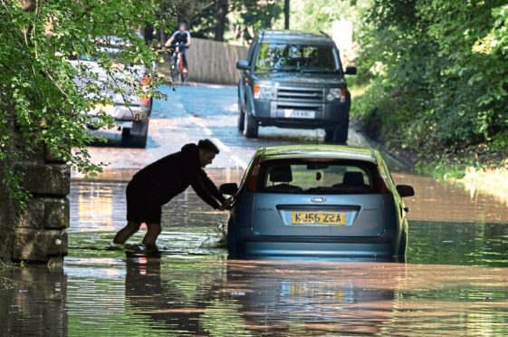 Mandatory Credit: Photo by Tina Norris/Shutterstock (10742192g)
A man abandons his car after driving it through flood water and becoming stuck on Station Road, Oakley in Fife
Flash flooding, Fife, UK - 12 Aug 2020