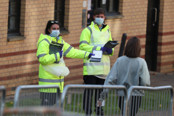 NHS staff hand out test kits to Glasgow University students as they arrive for testing at a pop up test centre at the Murano Street Student Village