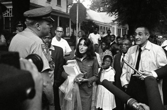 Joan Baez confronts a highway patrolman as she carries a girl’s books to school in Mississippi in 1966 as she campaigns against racial segregation