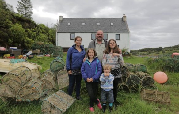 The McWhinney family, mum Jess and dad Ian with daughters Isla, left, Iona, and son Finlay, in front of their home on Dry Island off Gairloch, north west Highlands