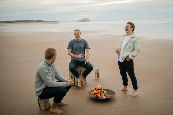 Rowers Lachlan, Jamie and Ewan MacLean enjoy a taste of their two unique whiskies on Tyninghame Beach, near North Berwick