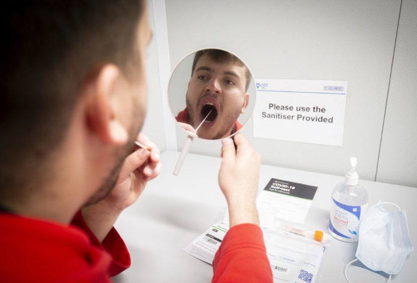Staff member Curtis Hughes demonstrates how to use the self-test kit