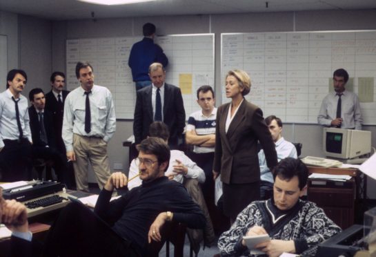 Actress Helen Mirren as Jane Tennison surrounded by men in TV’s Prime Suspect