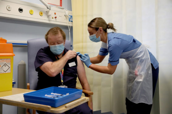 Deputy charge nurse Katie McIntosh administers the first of two Pfizer/BioNTech Covid-19 vaccine jabs to
Clinical Lead of Outpatient Theatres Andrew Mencnarowski.