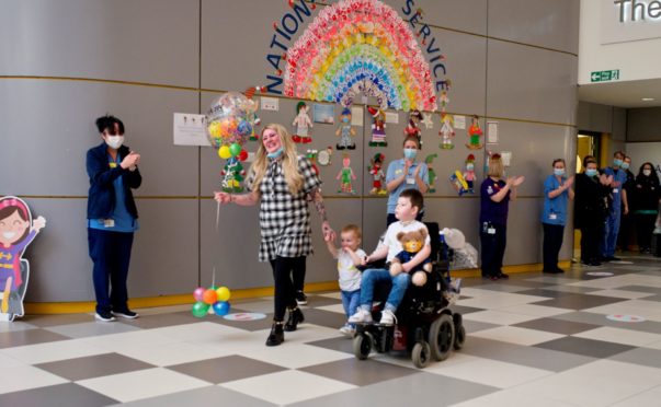 Oscar, right, leaves hospital with mum Megan and brother Theo