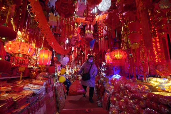 A masked vendor walks through a market decorated for Chinese New Year in Wuhan in China’s Hubei province. 
One year ago yesterday, a notice sent to smartphones in the city announced the world’s first coronavirus lockdown. Now life has largely returned to normal for the 11 million residents of the city where Covid-19 was first detected. Wuhan accounted for the bulk of China’s 4,635 deaths, but has been largely free of further outbreaks since lockdown was lifted on April 8. Questions, however, remain over the virus’s origins – and the authorities’ response.