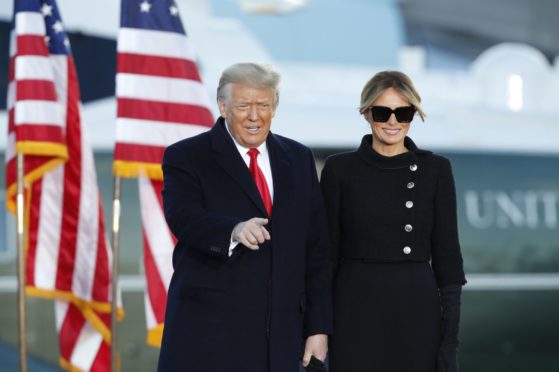 President Donald Trump gestures as first lady Melania Trump looks on before giving a speech to supporters at Andrews Air Force Base, Md., Wednesday, Jan. 20, 2021.