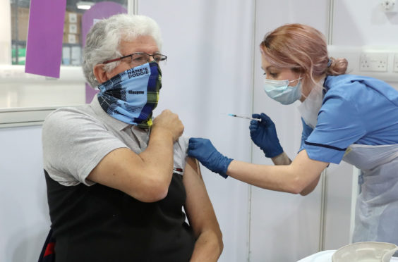 69 year old John Loch from Glasgow receives his Covid-19 vaccination from vaccinator Nicole Clark at the NHS Louisa Jordan Hospital in Glasgow