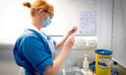 Nurse Eleanor Pinkerton prepares a coronavirus vaccine to be given to a health and care staff member at the NHS Louisa Jordan Hospital in Glasgow, as part of a mass vaccination drive by NHS Greater Glasgow and Clyde.
