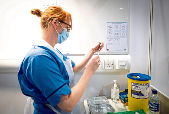 Nurse Eleanor Pinkerton prepares a coronavirus vaccine to be given to a health and care staff member at the NHS Louisa Jordan Hospital in Glasgow, as part of a mass vaccination drive by NHS Greater Glasgow and Clyde.