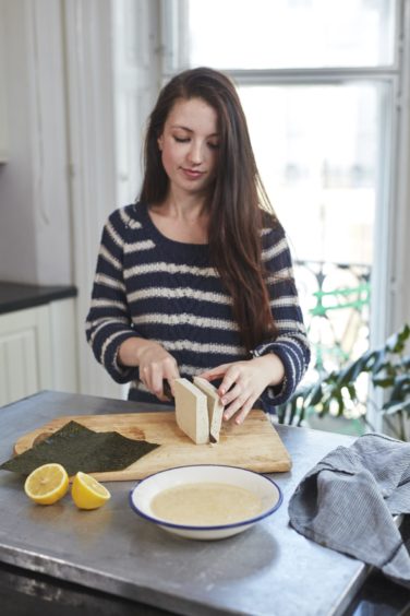 Aimee Ryan at work in her kitchen, cooking a dish of tofish and chips