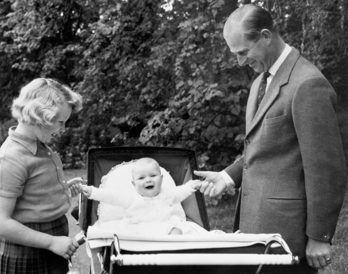 The Duke of Edinburgh with Princess Anne and Prince Andrew in his pram, in the grounds of Balmoral.