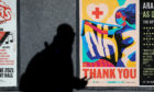 A person walks passed an advertising board in Glasgow showing a Thank You NHS poster