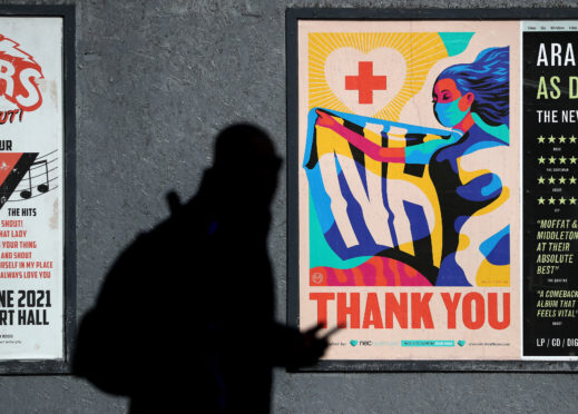 A person walks passed an advertising board in Glasgow showing a Thank You NHS poster