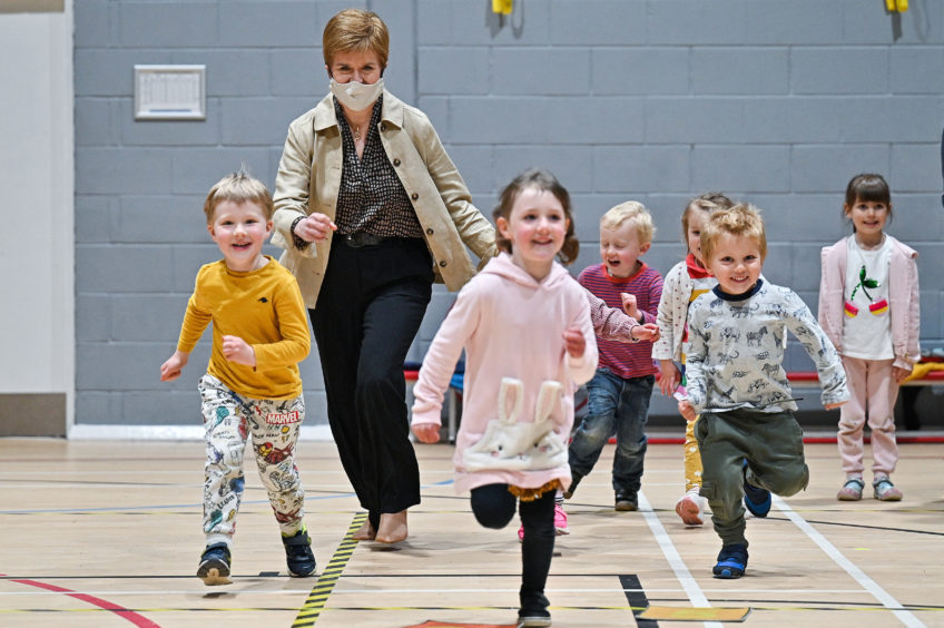 Nicola Sturgeon gives a check-up to "Dentosaurus" during a visit t Thornliebank Dental Care