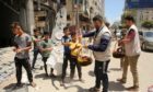 Aid workers hand out fruit and sweets to Palestinian children amid the rubble of Gaza City following days of Israeli air strikes