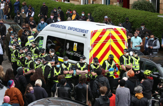 Police by an immigration van in Kenmure Street, Glasgow which is surrounded by protesters