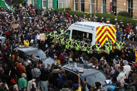 Lawyer Aamer Anwar speaks to protesters blocking the road as police surround an immigration van in Kenmure Street, Glasgow