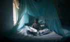 A child underneath a mosquito net, Kenya