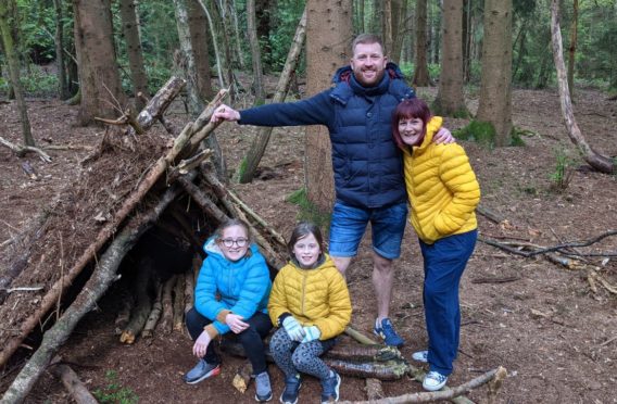 Claire Spreadbury and her family, outside the den they built in the forest