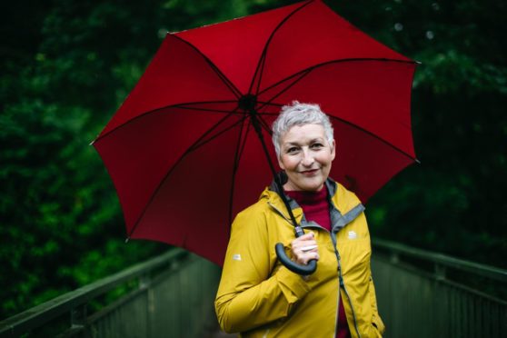 Actress, Blythe Duff shelters from the rain in a park in Cambuslang, Glasgow