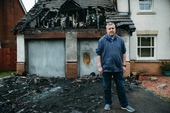 Councillor, Graeme Campbell standing outside his house, which was firebombed this week, causing considerable fire damage, as well as destroying his cars.