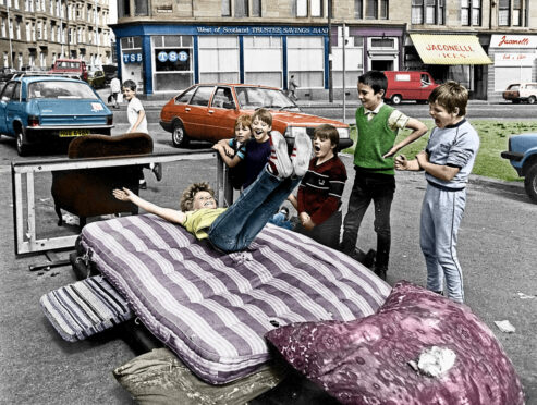 Children in Maryhill, Glasgow, enjoying some impromptu but spectacular high jump fun in a 1980s summer are framed by the late, great newspaper photographer Ronnie Anderson.                       (Colourisation - John Wilkie)