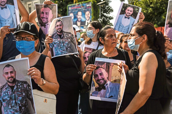 Families of the blast victims hold their pictures as Lebanon marks the first anniversary of the blast on Wednesday.