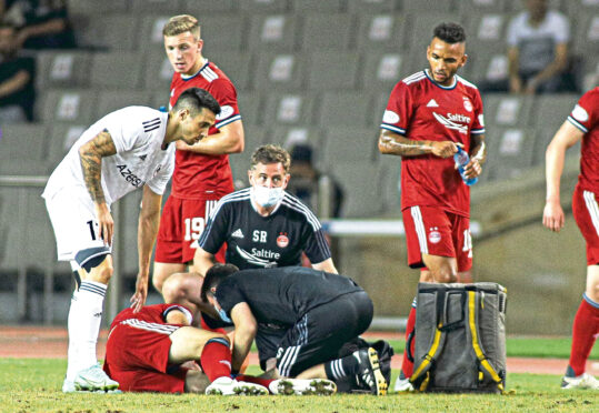 Andrew Considine is tended to by Aberdeen’s medical team after going down injured in Baku