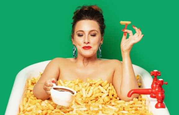 Grace Dent poses in a bath of chips