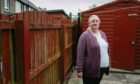 Helen Dillet next to the disputed fence in the garden of her lifelong home in Fauldhouse