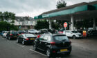 Cars queue at Morrisons petrol station on the south side of Glasgow yesterday as drivers panic-buy