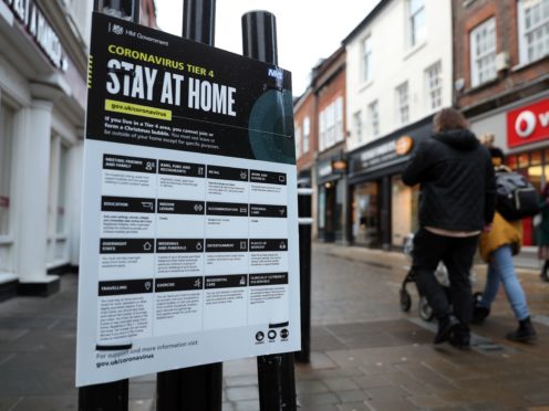 People make their way past a Government coronavirus sign (PA)
