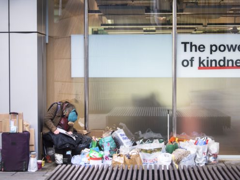 A homeless person sits in a window in the City of London (Victoria Jones/PA)