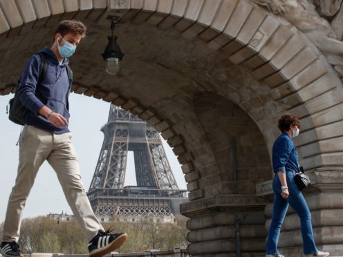 People wearing masks to prevent the spread of Covid-19 cross the Bir Hakeim bridge in Paris (Michel Euler/PA)