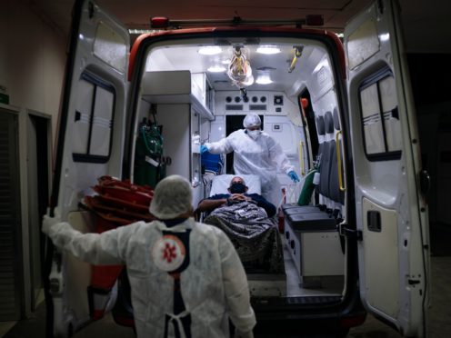 Emergency Care Service workers move a Covid-19 patient to an ambulance in Brazil (Felipe Dana/AP)