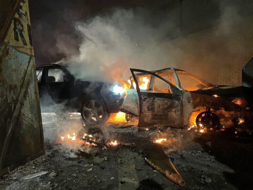 Cars have been set alight during another night of trouble in Belfast, including these which people from the loyalist side tried to drive through the Peace Gates in Lanark Way (Liam McBurney/PA)